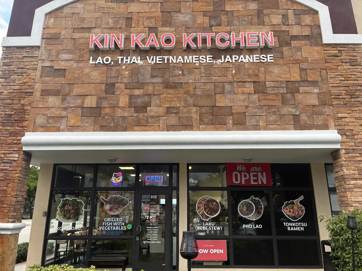 The Kin Kao Kitchen storefront with its dish decals and We are OPEN banner